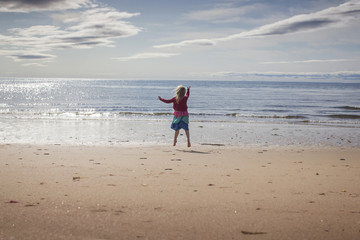Young girl leap for joy on a beach 