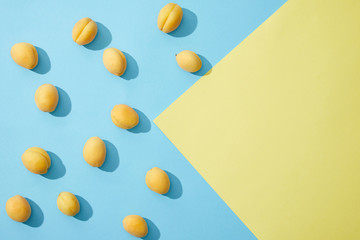 top view of ripe tasty apricots on blue and yellow background