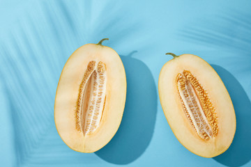 top view of halves of fresh sweet ripe melon on blue