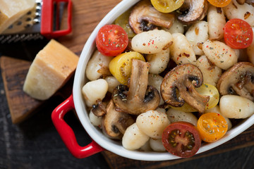 Close-up of italian gnocchi with fried champignons and fresh sliced tomatoes, view from above, horizontal shot