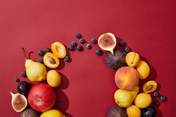 top view of various fresh ripe sweet tasty fruits on red background
