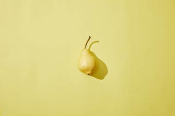 top view of single fresh ripe pear on yellow background