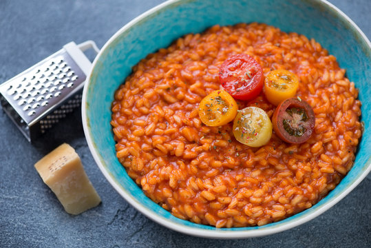 Risotto with tomatoes served in a turquoise bowl, elevated view, studio shot