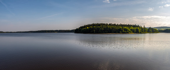 Panoramic view of summer landscape with lake under blue sky