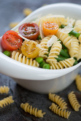 Bowl of fusilli pasta with vegetables and cheese, selective focus, close-up