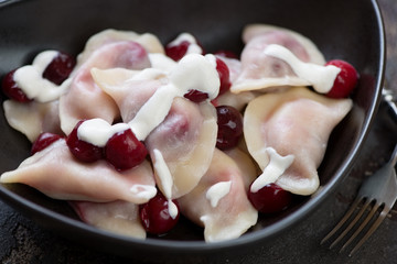 Close-up of boiled vareniki dumplings stuffed with cherries and topped with sour cream