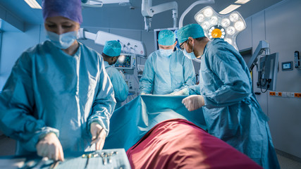 Diverse Team of Professional surgeon,  Assistants and Nurses Performing Invasive Surgery on a...