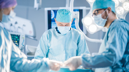 Shot in the Operating Room, Assistant Hands out Instruments to Surgeons During Operation. Surgeons Perform Operation. Professional Medical Doctors Performing Surgery.