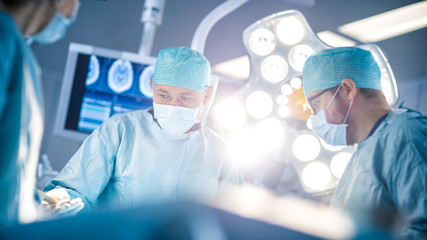 Low Angle Shot in the Operating Room, Assistant Hands out Instruments to Surgeons During Operation....
