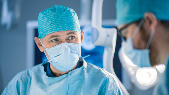 Portrait Shot of a Surgeon Thinking About Saving Life of a Patient. Diverse Team of Professional surgeons, Assistants and Nurses Performing Invasive Surgery on a Patient in the Operating Room.