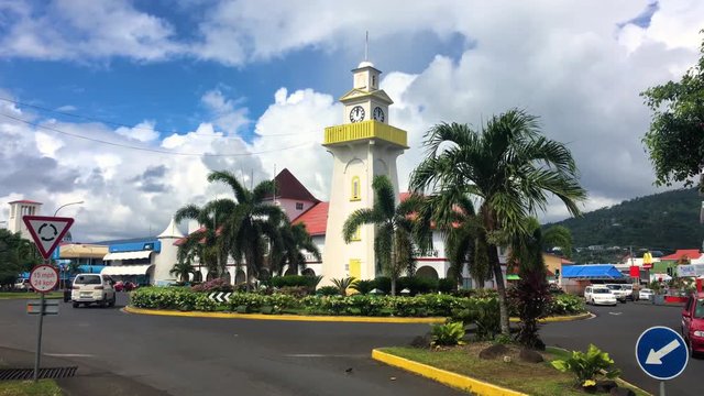 Apia, Samoa, Cars going in and out of roundabout main square with WWII monument in the center. Colonial Style building