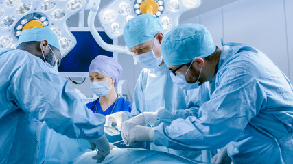 In the Hospital Operating Room Diverse Team of Professional Surgeons and Nurses Suture Wound after Successful Surgery.