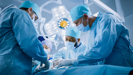 In the Hospital Operating Room Diverse Team of Professional Surgeons and Nurses Suture Wound after...