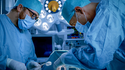 In the Hospital Operating Room Diverse Team of Professional Surgeons and Nurses Suture Wound after...