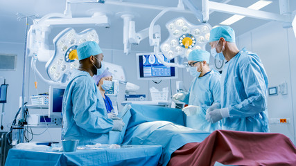 Diverse Team of Professional Surgeons Performing Invasive Surgery on a Patient in the Hospital Operating Room. Surgeons Use Instruments.