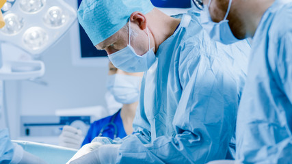 Fototapeta premium In the Hospital Operating Room Diverse Team of Professional Surgeons and Nurses Suture Wound after Successful Surgery.