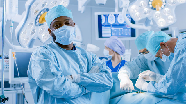 Diverse Team of Professional Surgeons Performing Invasive Surgery on a Patient in the Hospital Operating Room. Surgeons Use  and other Instruments.