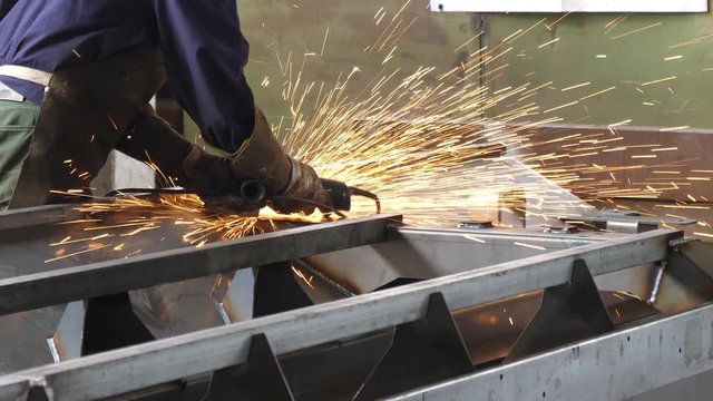 Worker sawing metal with disk grinder in workshop 4K