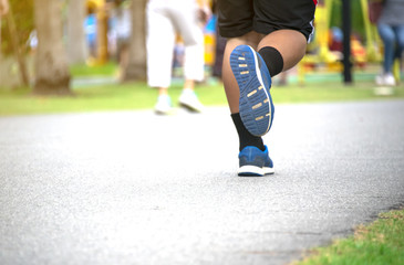 Fototapeta premium Running shoes and strong athletic legs jogging in health public park