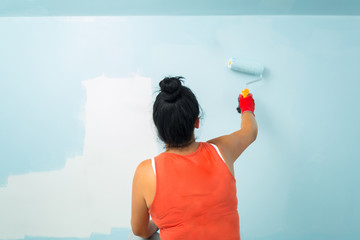 Woman at painting a room with paint roller