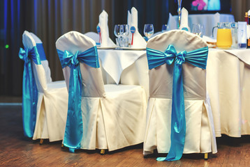 Wedding chairs decorated with blue bows at restaurant