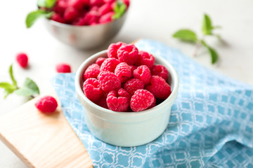 Bowl with delicious raspberries on table