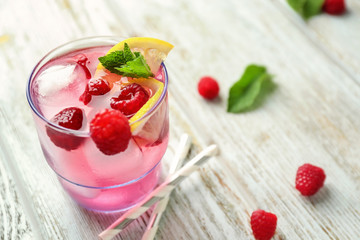 Glass of fresh raspberry mojito on wooden table
