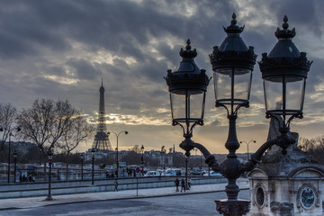 Fototapeta premium Three unlit street lamps at dusk, with the Eiffel Tower in the background