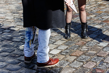 Female and male feet on a stone pavement. Man is in dirty jeans.