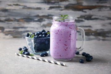 Mason jar of tasty blueberry smoothie on light table