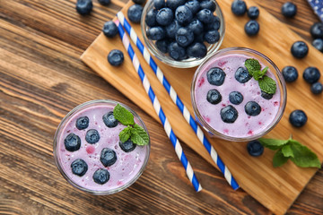 Fototapeta na wymiar Glasses of tasty blueberry smoothie on wooden table