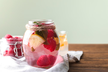 Fototapeta na wymiar Glass jar of fresh raspberry mojito on wooden table