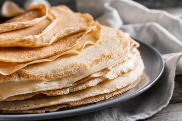 Stack of tasty thin pancakes on plate, closeup