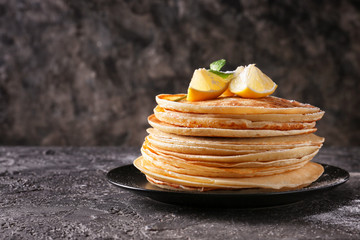 Plate with stack of tasty thin pancakes on table