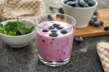 Glass of tasty blueberry smoothie on table