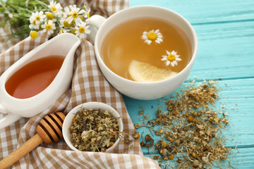 Cup of delicious camomile tea and honey on wooden table