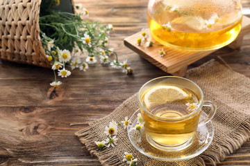 Cup of delicious camomile tea on wooden table