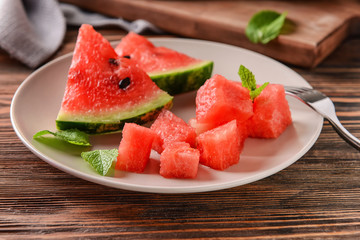 Plate with sweet watermelon slices on wooden table