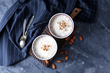 Bowls with delicious rice pudding and nuts on board