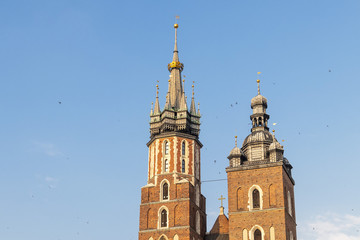 Fototapeta na wymiar Detail of domes of Gothic Saint Mary Basilica in city center of Krakow, Poland, at evening with Swallows flying