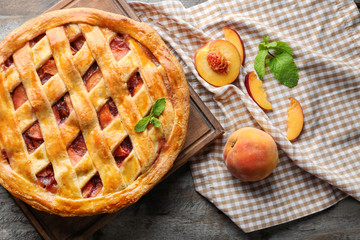 Board with delicious peach pie on wooden table