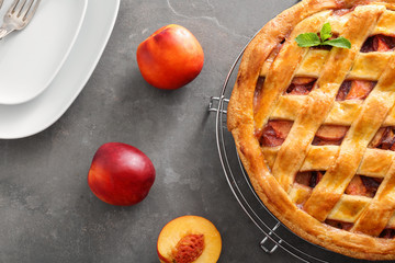 Cooling rack with delicious peach pie and plates on table