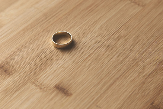A gold ring on a wooden table top. This image can be used to represent marriage or commitment. 