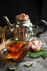 Vintage silver tea brewer. Transparent cup with tea. Dry flowers. Dark gray background. Close-up