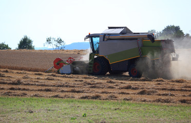 Fototapeta premium Mähdrescher bei der Weizenernte auf einem trockenen staubigen Feld
