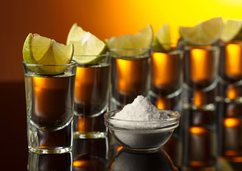 Gold tequila on a black reflective background.