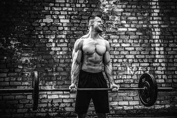 Muscular fitness man doing deadlift a barbell over his head in outdoor, street gym. Functional...