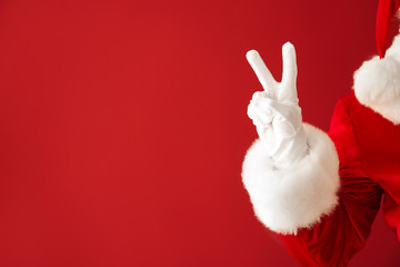 Santa Claus showing victory gesture on color background, closeup