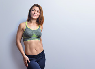Beautiful fitness woman showing abdominal muscles  on a studio background.