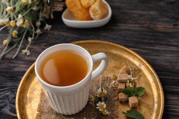 Cup of delicious camomile tea on table